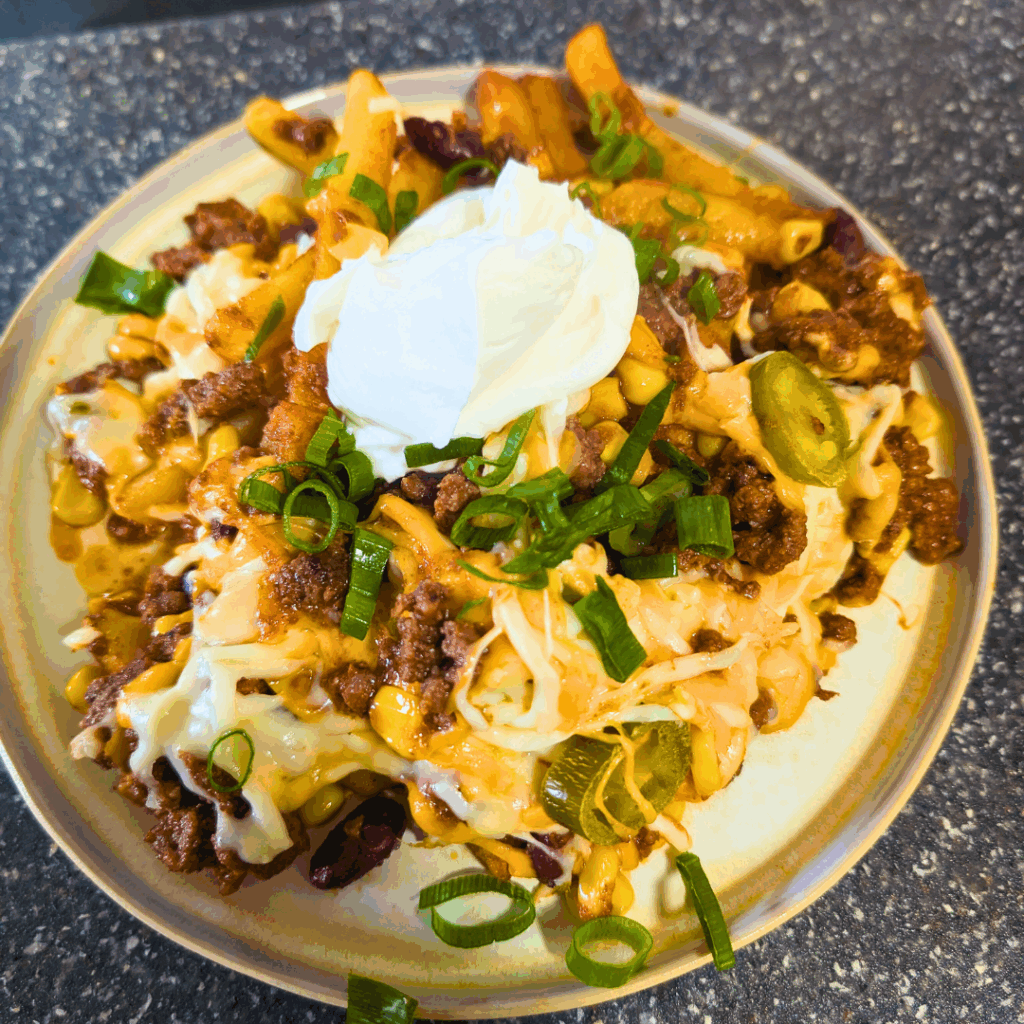 Cheesy beef casserole with jalapenos, sour cream, and green onions on a beige plate.