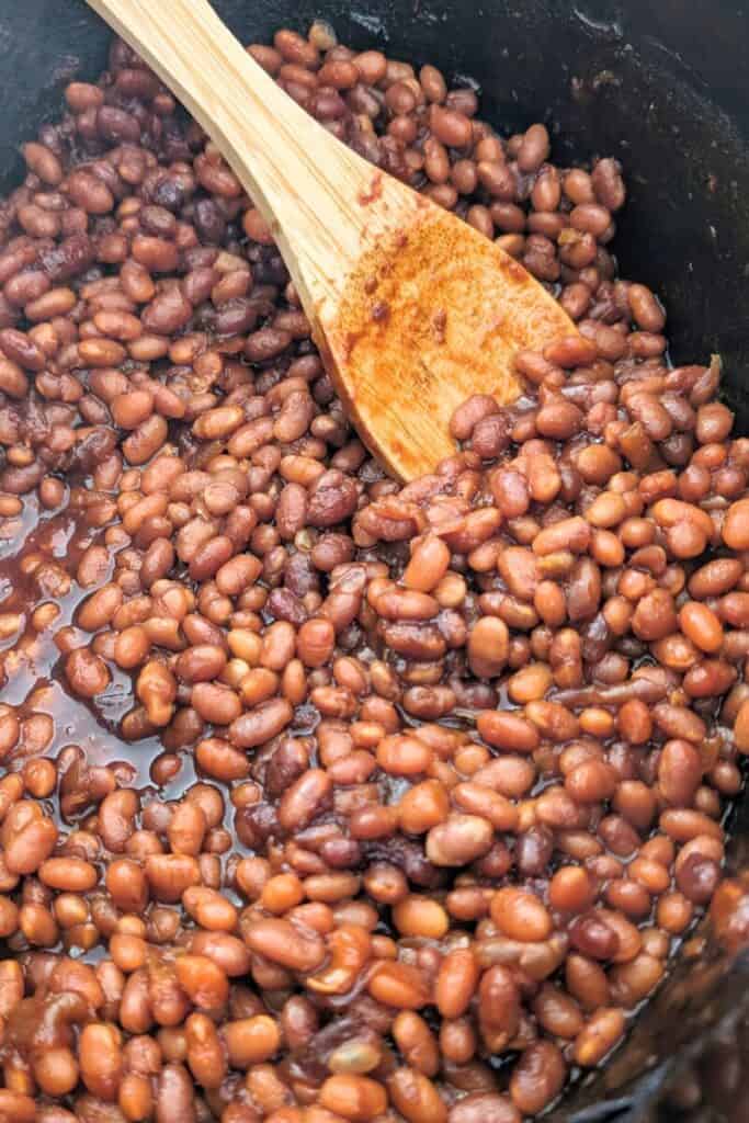 stirring the baked beans as they cook in slow cooker