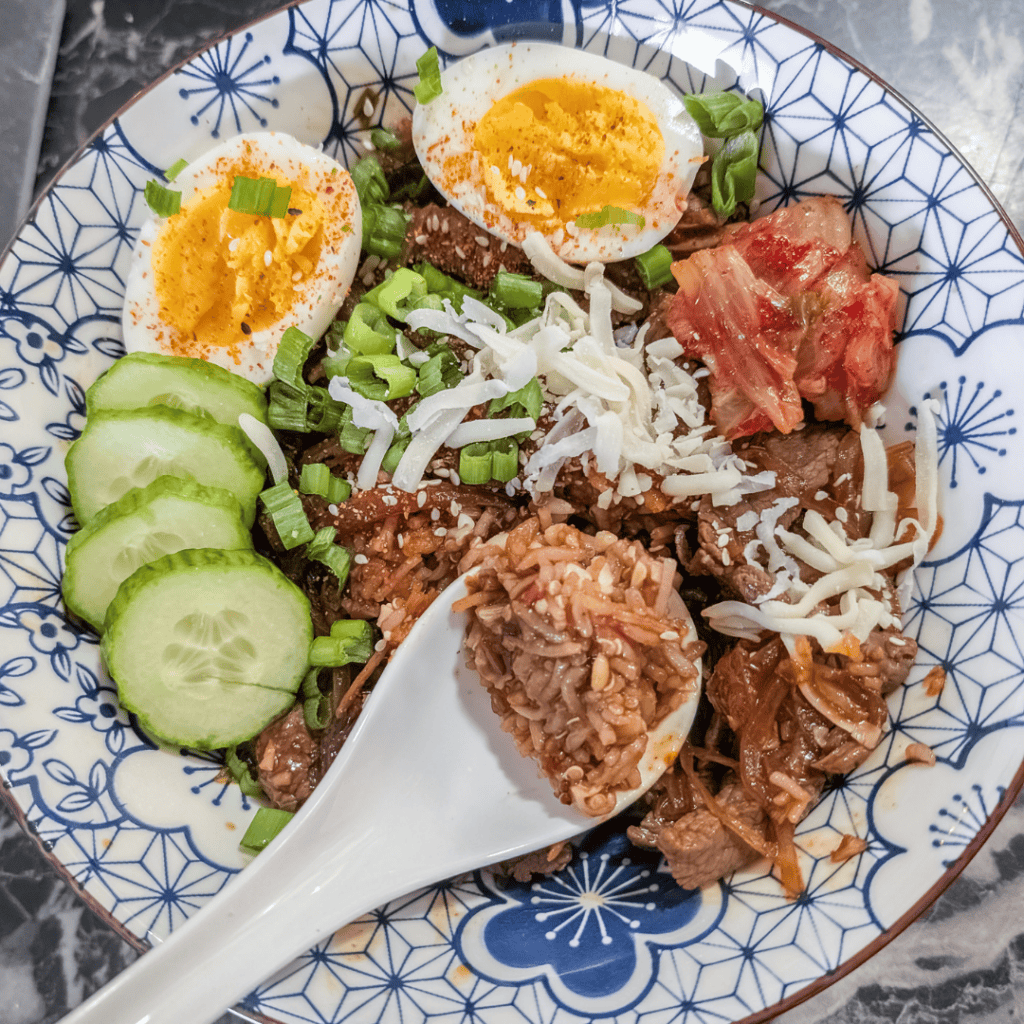 Authentic Gyudon with tender beef, rice, boiled eggs, and fresh vegetables in a traditional bowl.