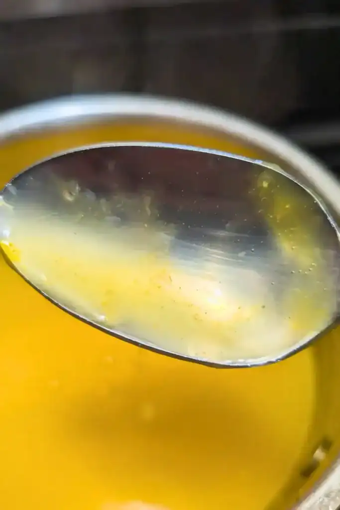 a silver spoon coated in the orange sauce to show how thick it should be