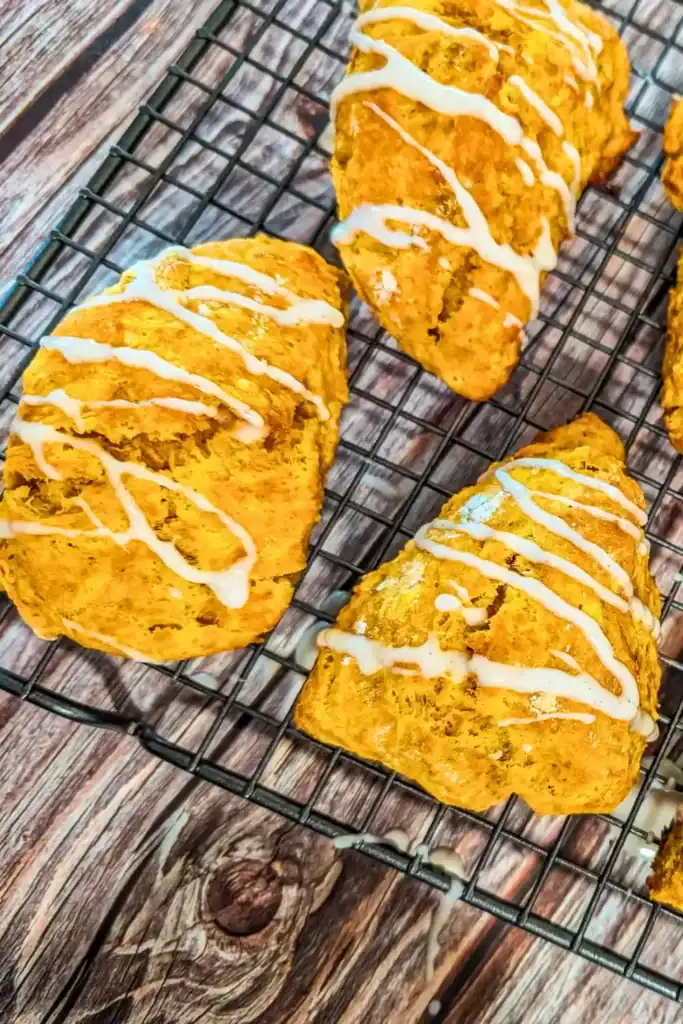finished baked pumpkin scones on wire baking rack with pumpkin spice drizzled icing