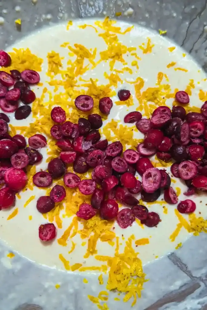 adding halved frozen cranberries to the orange zest pancake batter