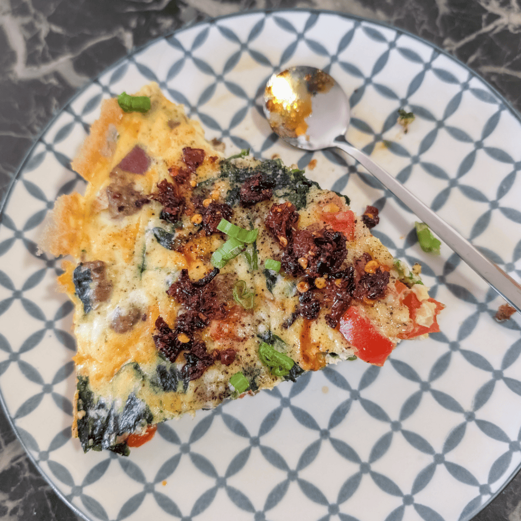 Delicious sausage and spinach frittata served on a patterned plate.