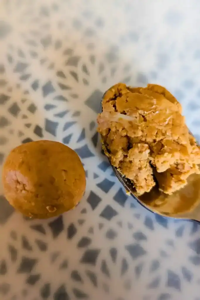 one one inch wowbutter ball formed on wax paper on blue and white plate and spoon showing how much to scoop for each ball