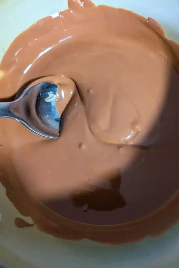 the melted milk chocolate after being stirred in bowl with spoon in it