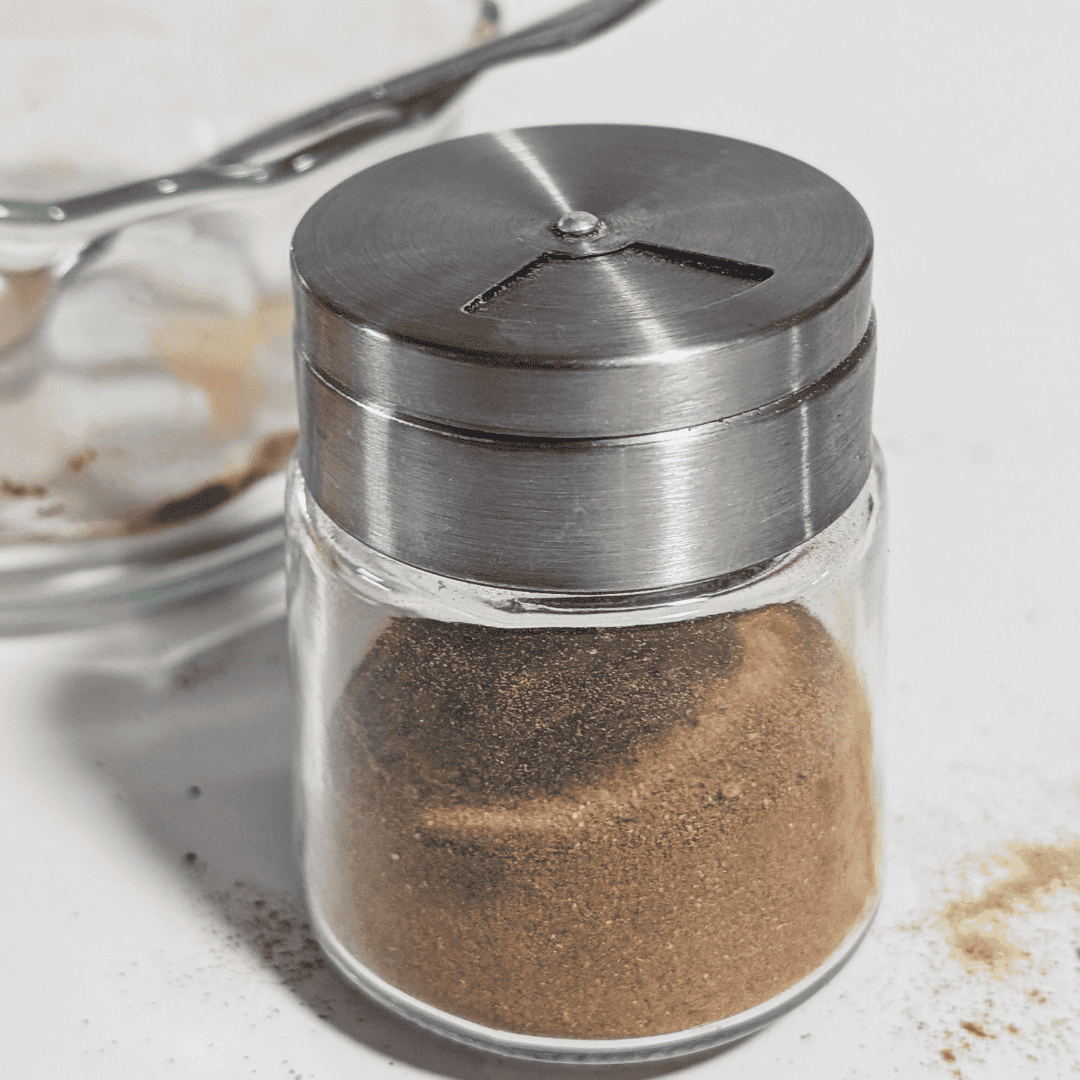 Shaker spice jar with black lid and ground spice in glass container.