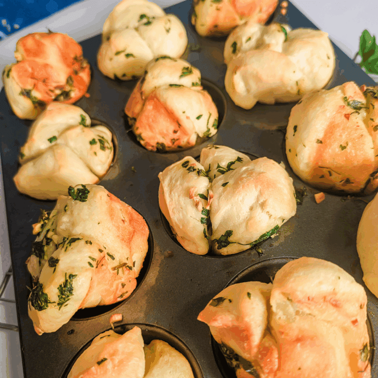 Fluffy herb-infused cheese muffins baked in a muffin tin for flavorful snack or breakfast options.