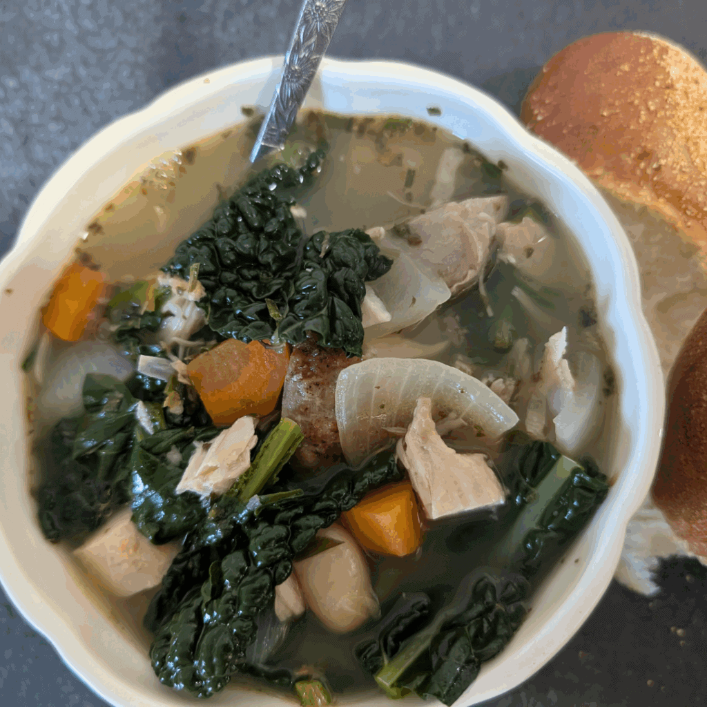 Savory chicken vegetable soup with kale and carrots in a white bowl for comforting, healthy meals.