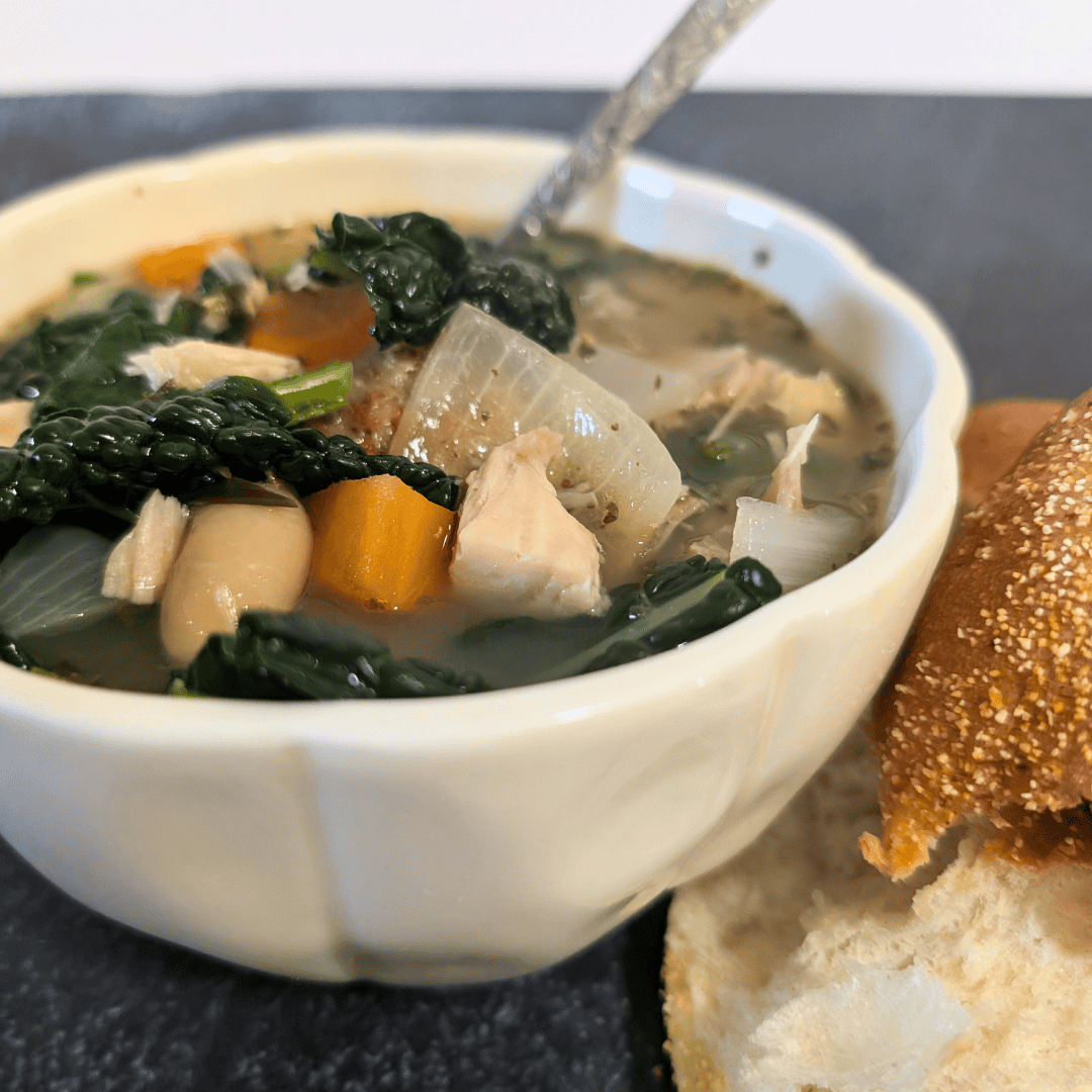 Canned vegetable soup with chicken and bread on a dark background.