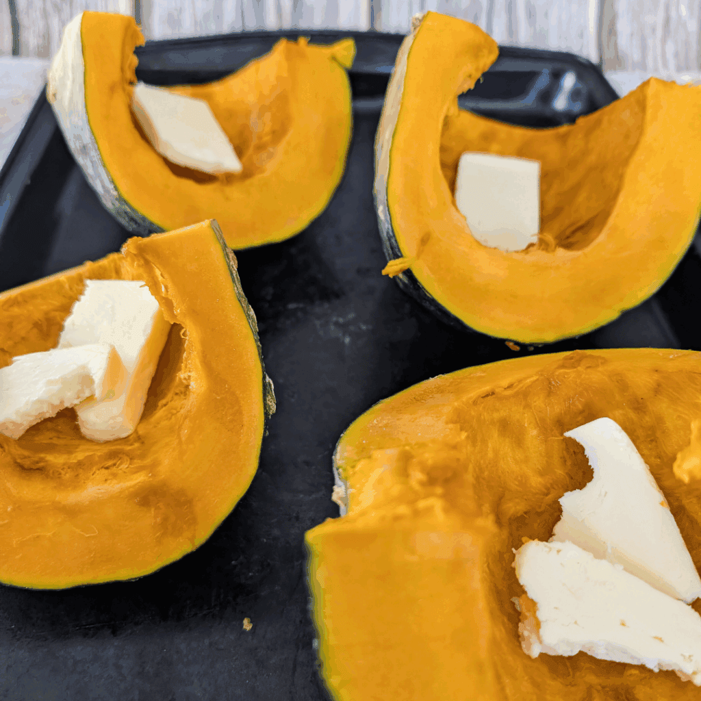 Fresh pumpkin with butter filling on black tray.