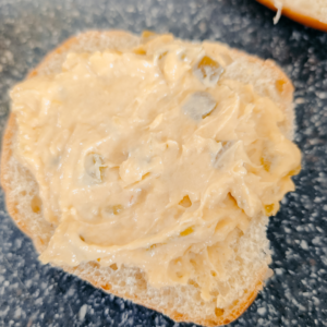 Cheddar cheese sauce spread on toasted bread slice, perfect for burgers or snacks.