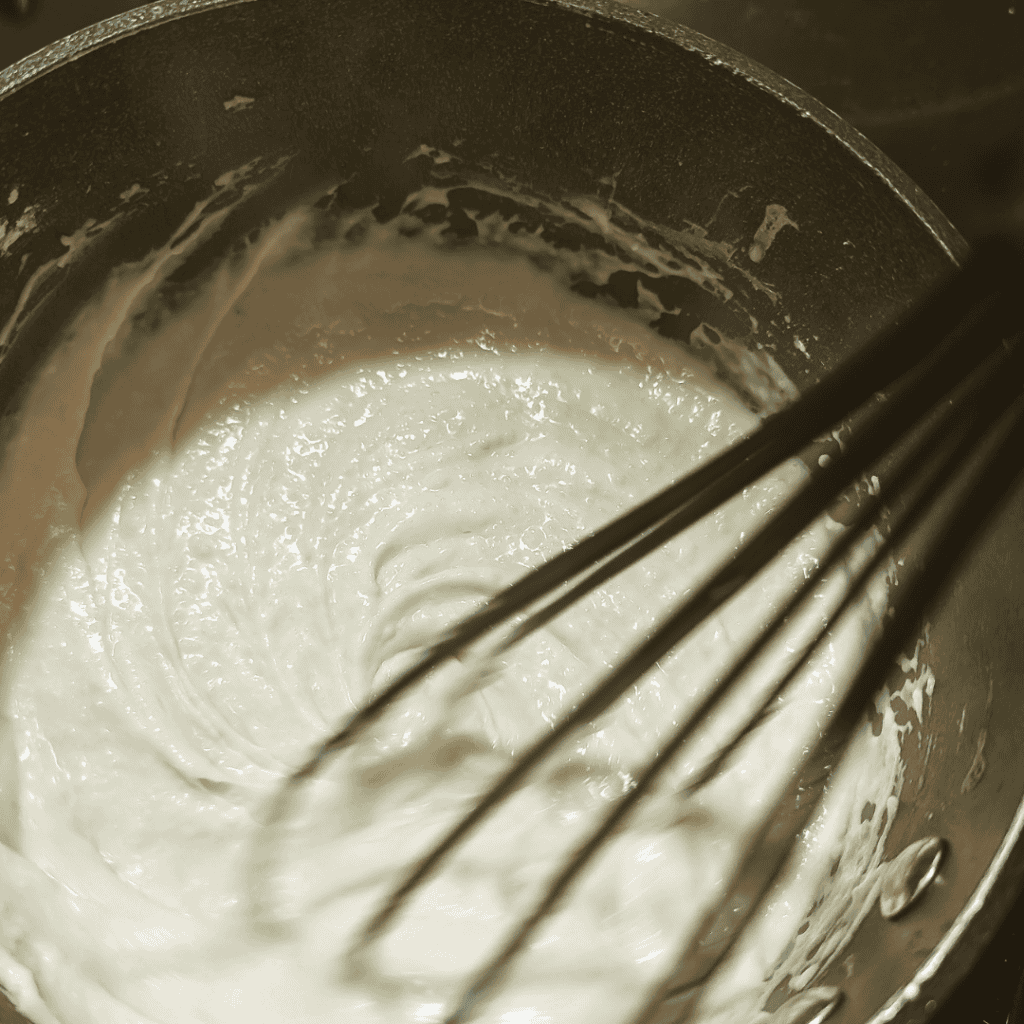 Thick and creamy cheddar cheese sauce in a saucepan, perfect for burgers.