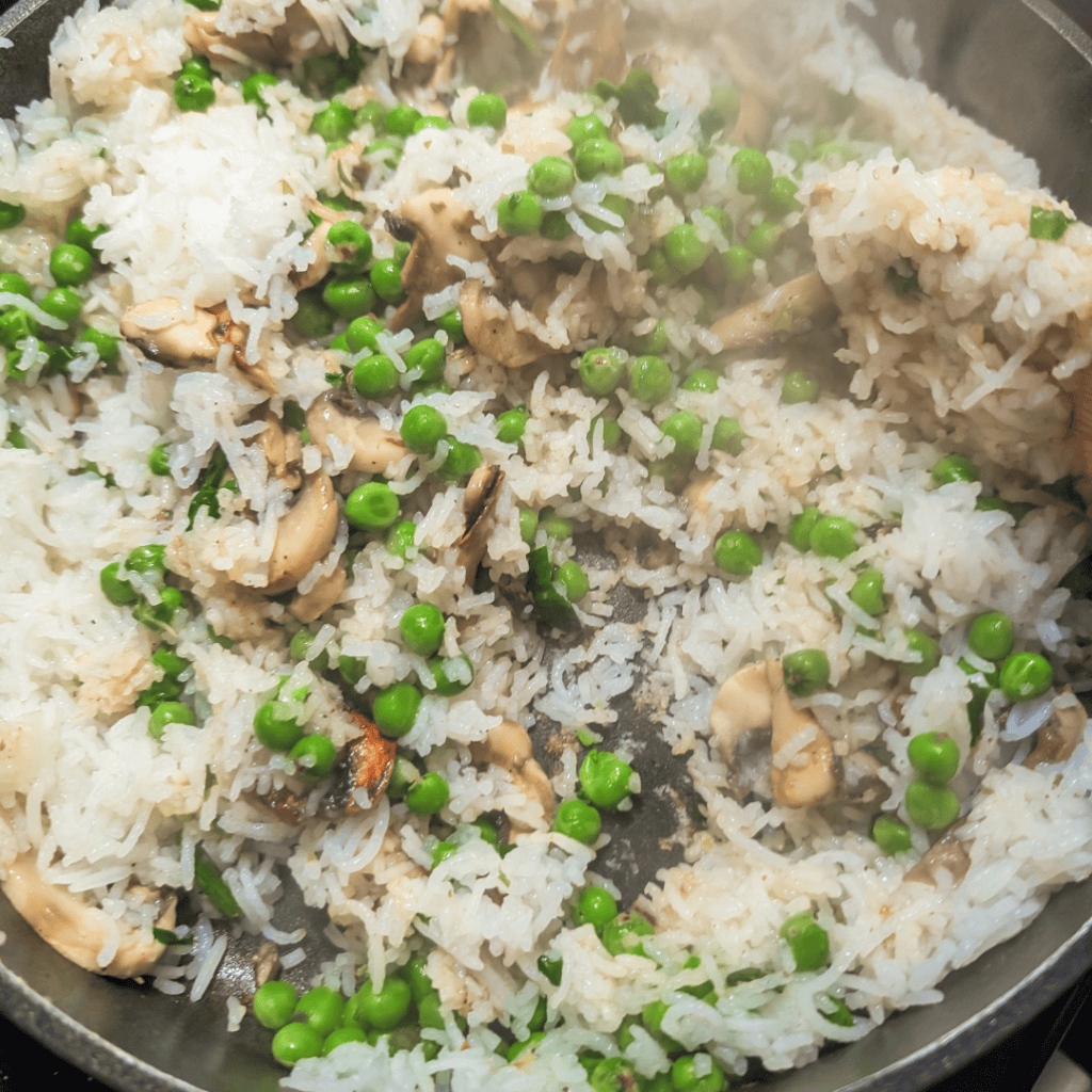 Mushroom rice pilaf with ramps and peas in a skillet.