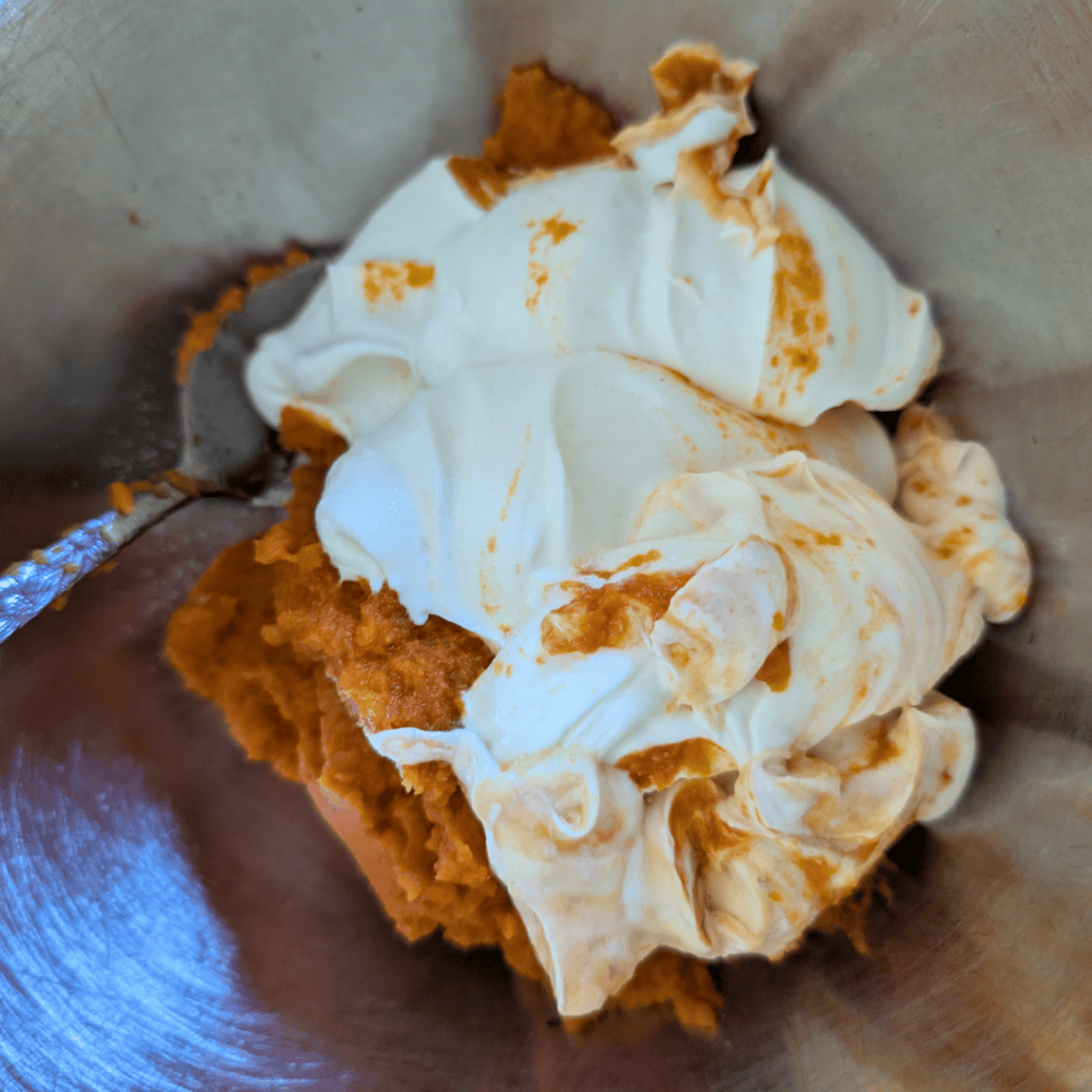 measuring the plain greek yogurt and pumpkin into bowl