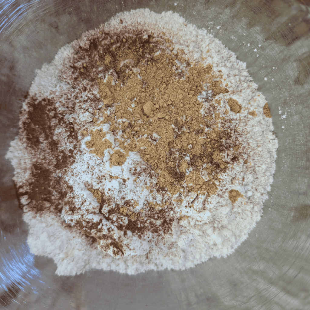 adding ginger powder to dry ingredients for cake batter