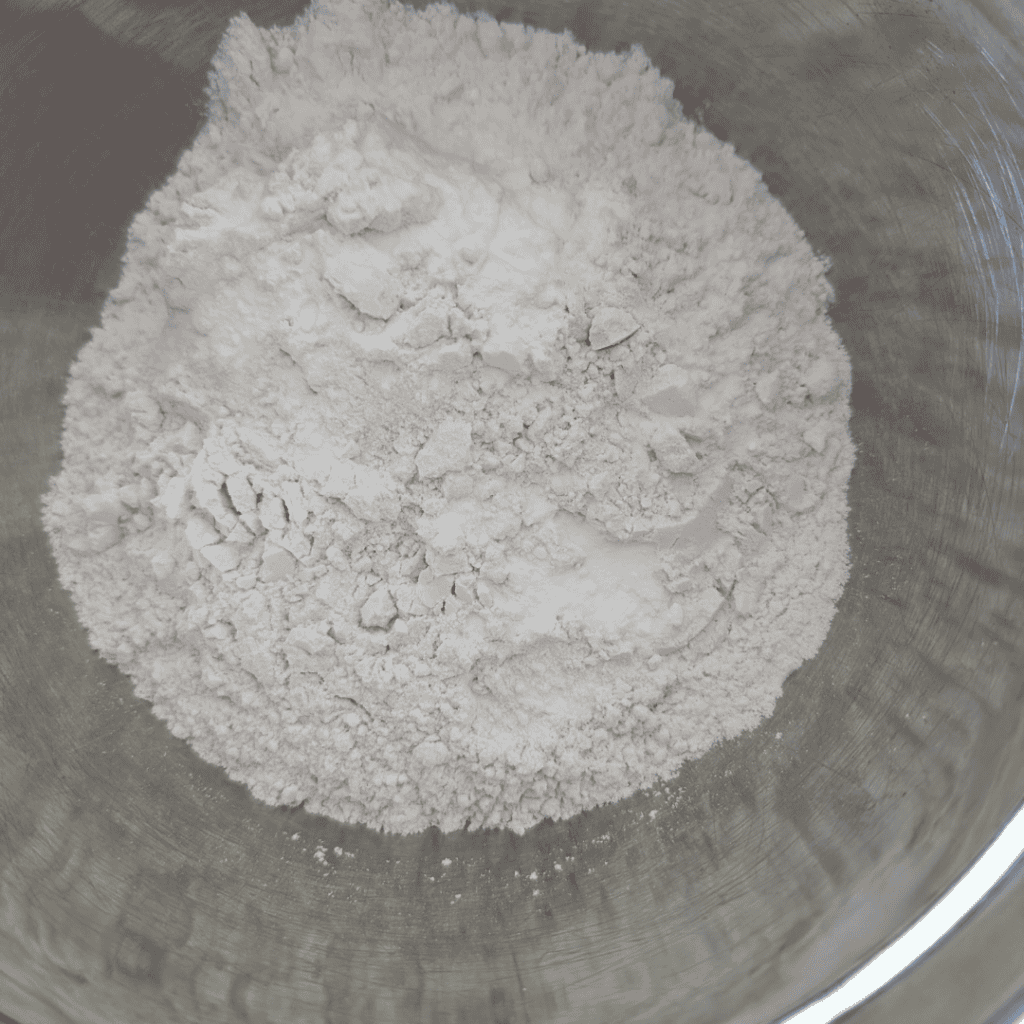 measured flour and baking soda in stainless steel mixing bowl