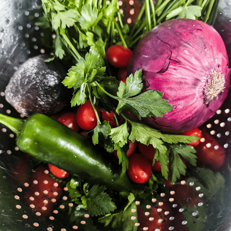 Fresh vegetables including red onion, cherry tomatoes, cilantro, and a green chili.